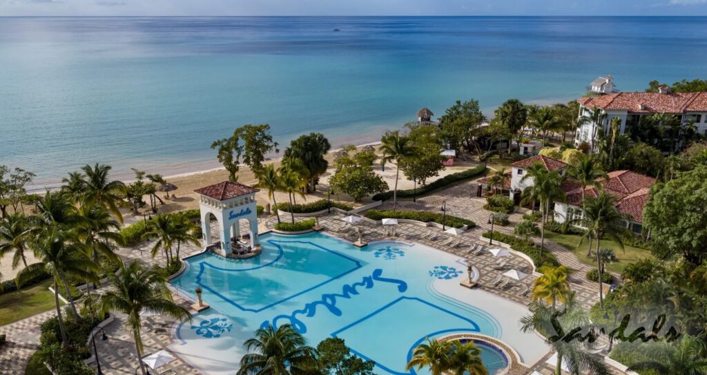 A beautiful sky view of the main pool of Sandals South Coast - Jamaica with a great view of blue water ocean beach